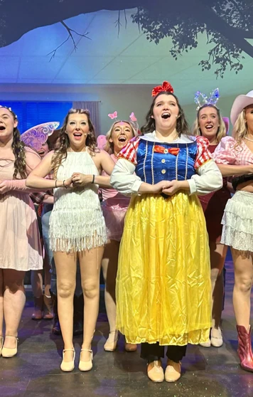 Ensemble cast dressed in colorful costumes, singing joyfully on stage during a musical theatre production. Ensemble cast dressed in colorful costumes, singing joyfully on stage during a musical theatre production.